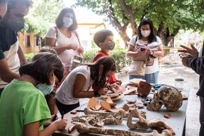 Varios niños aprenden a catalogar las piezas halladas en la excavación.